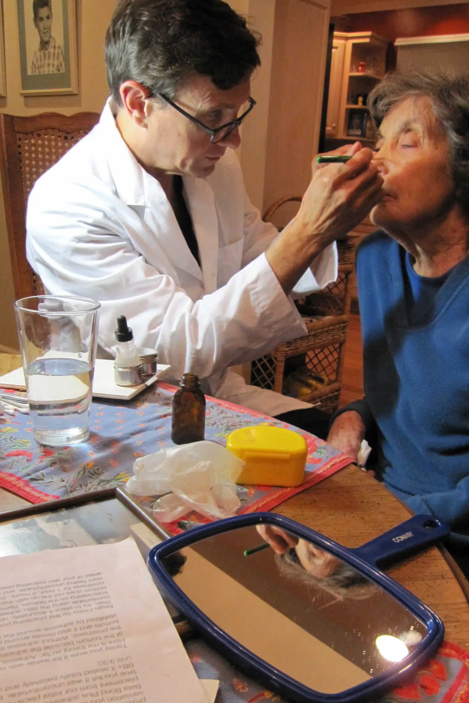 Doctor applying makeup to elderly woman.