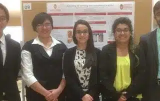 Three women standing next to each other in front of a poster.