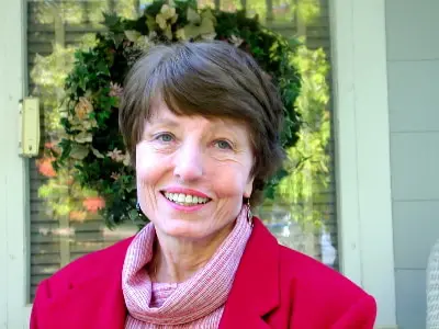 A woman in a red jacket smiling for the camera.