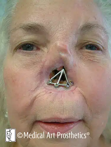 A woman with an iron triangle shaped nose ring.