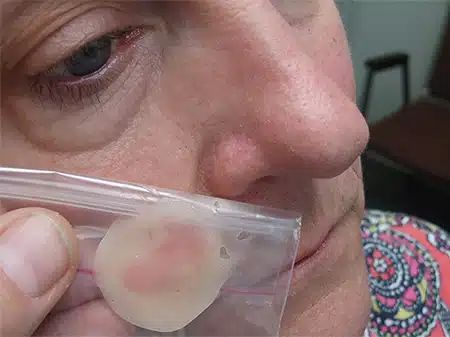 A woman holding an ear tag in her mouth.
