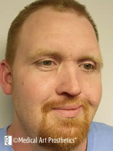 A man with red hair and beard wearing blue shirt.