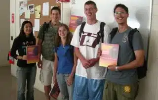 A group of people standing in front of a bulletin board.