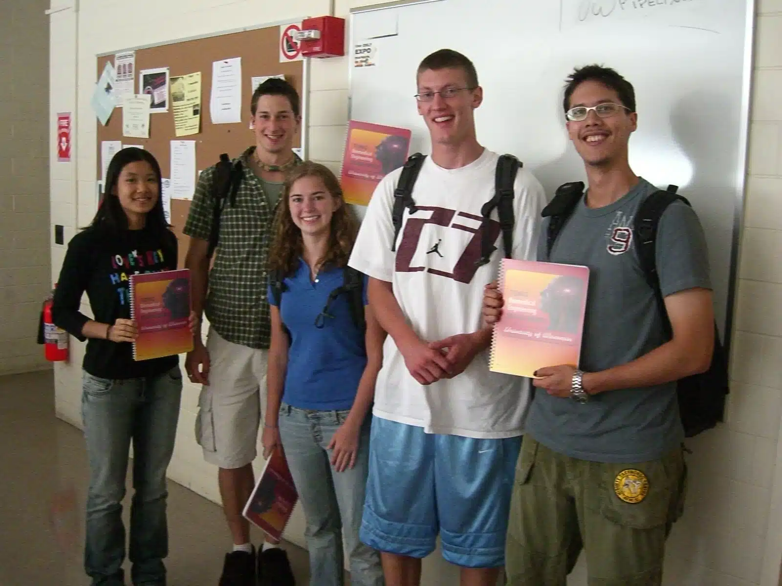 A group of people standing in front of a bulletin board.