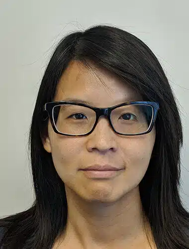 A woman with glasses is smiling for the camera.