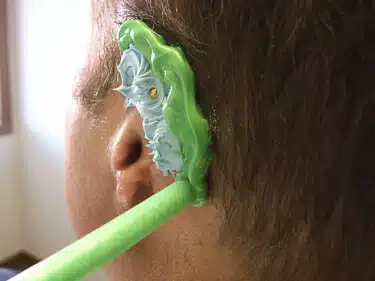 A person with green toothbrush in his mouth.