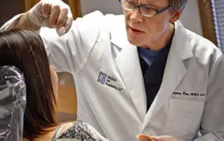 A doctor is holding something to the woman 's face.