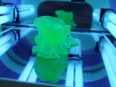 A green object is being made in the 3 d printer.